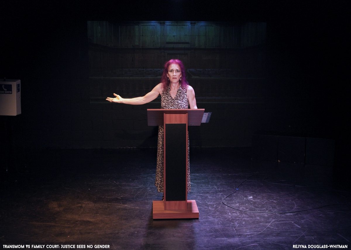 Rejyna at a courtroom podium on stage in a pool of purple light